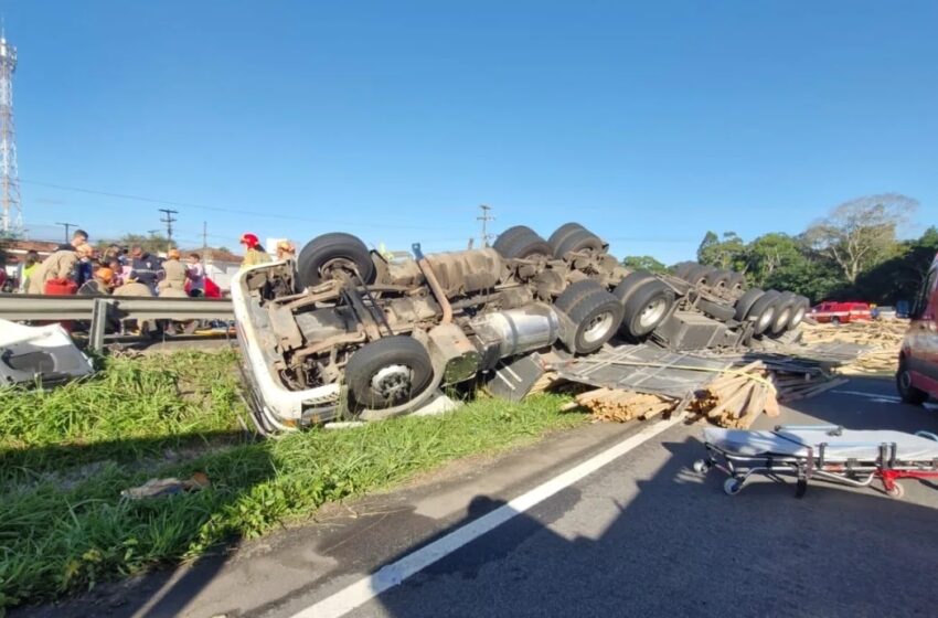  Caminhão carregado de madeira capota na BR-230, em Santa Rita, e motorista fica preso às ferragens